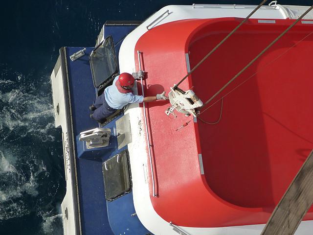 Hooking up the stern of the tender to lift it back aboard